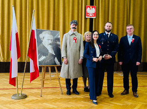 Policjant stoi wraz z kadrą szkoły.