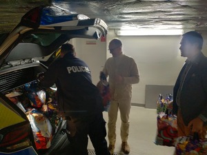 Policjant i burmistrzowie pakują paczki do samochodu.