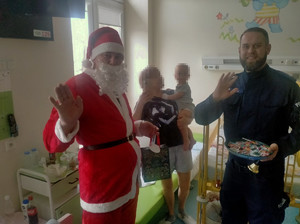 Policjant z mikołajem i innymi osobami.