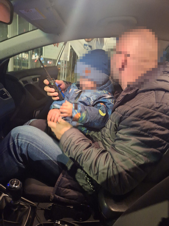 Policjant trzyma chłopca na kolanach.