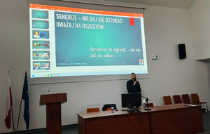 Policjant stoi przed osobami starszymi.