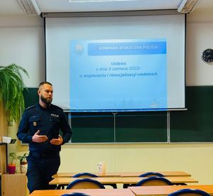 Policjant stoi przed tablicą.