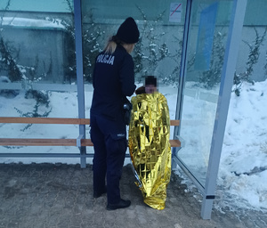 Policjantka stoi przy osobie bezdomnej.