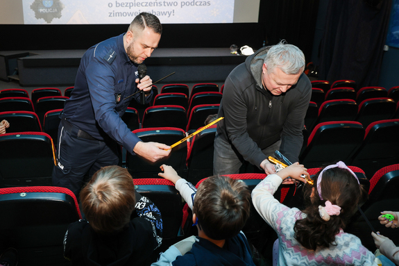 Policjant i kierownik SCB rozdają odblaski.