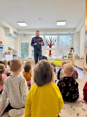 Policjant stoi przed dziećmi.