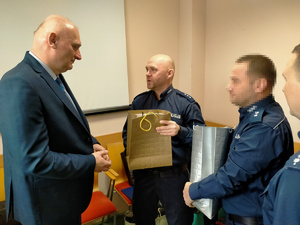 Policjanci wręczają prezenty.