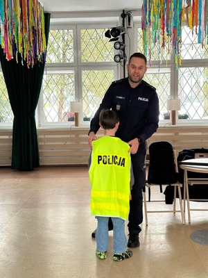 Policjant trzyma kamizelkę.