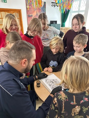 Policjant robi odbitki linii papilarnych.