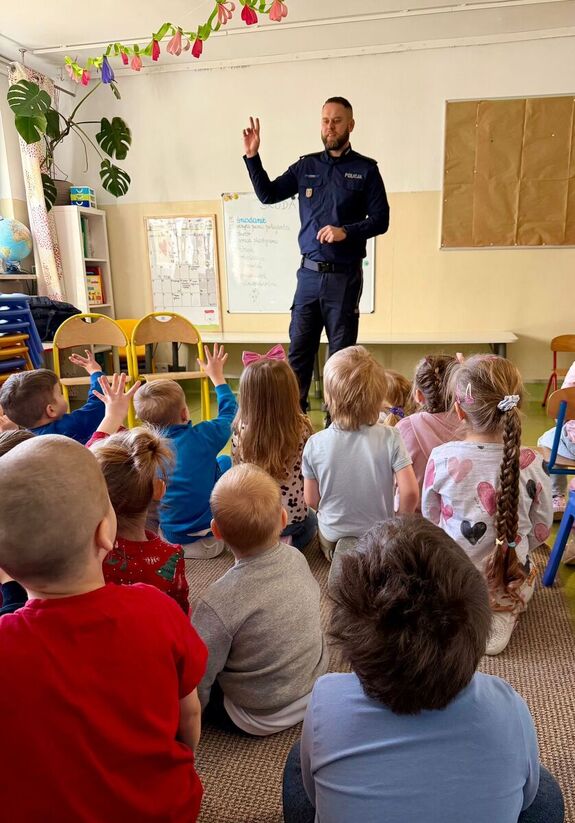 Policjant stoi przed dziećmi.