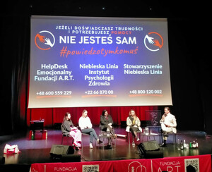 Osoby siedzą na scenie.