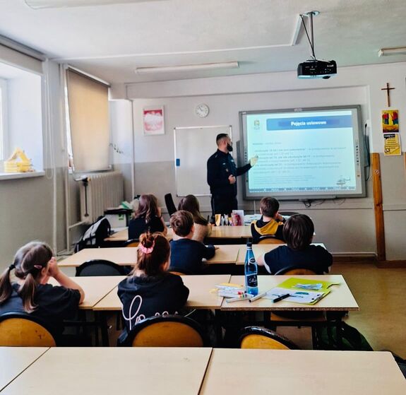 Policjant stoi przed uczniami.