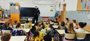 Policjant stoi przed dziećmi.