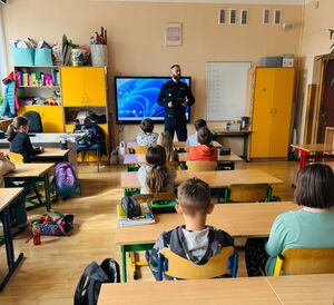 Policjant stoi przed dziećmi.