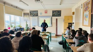 Policjant stoi przed uczniami.