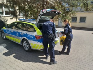 Policjanci pakują książki do radiowozu.