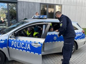 Policjant nachyla się do radiowozu.