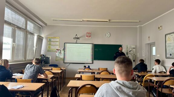 Policjant stoi przed tablicą.