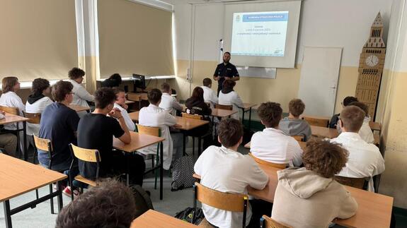 Policjant stoi przed uczniami.