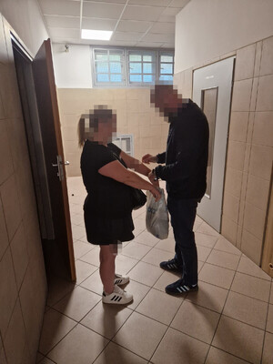 Policjant zakłada kajdanki kobiecie.