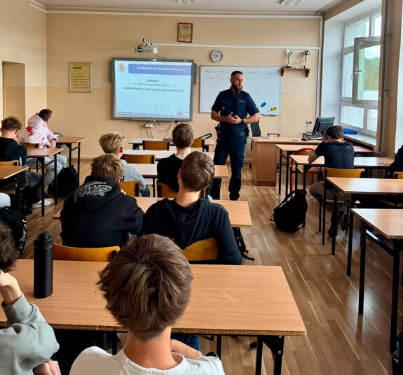 Policjant stoi przed uczniami.